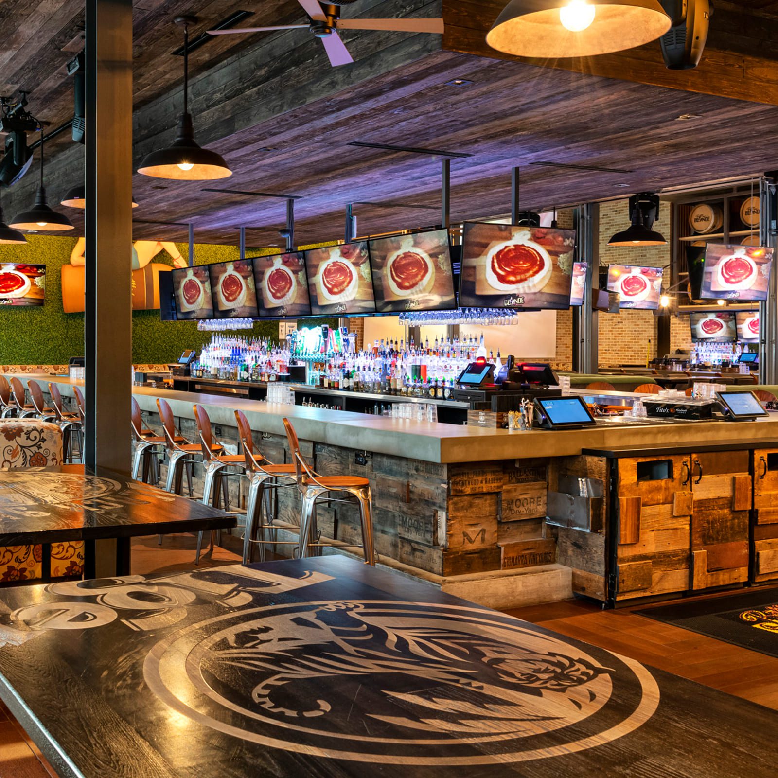 Island bar with reclaimed crate-wood front and logo-engraved tables at Bottled Blonde Houston, by Lion Craft